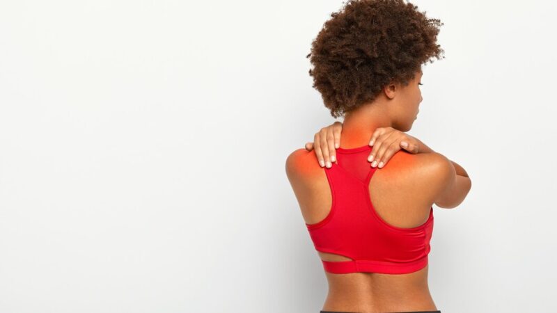 Une femme en brassière rouge qui se tient les épaules