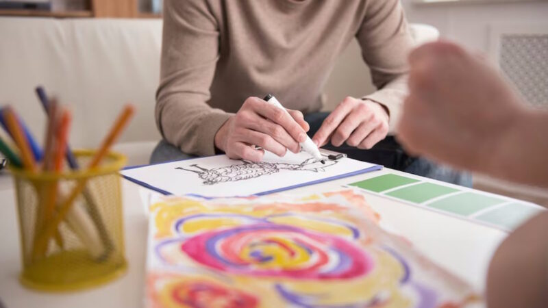 Un homme qui dessine avec un feutre sur un papier blanc