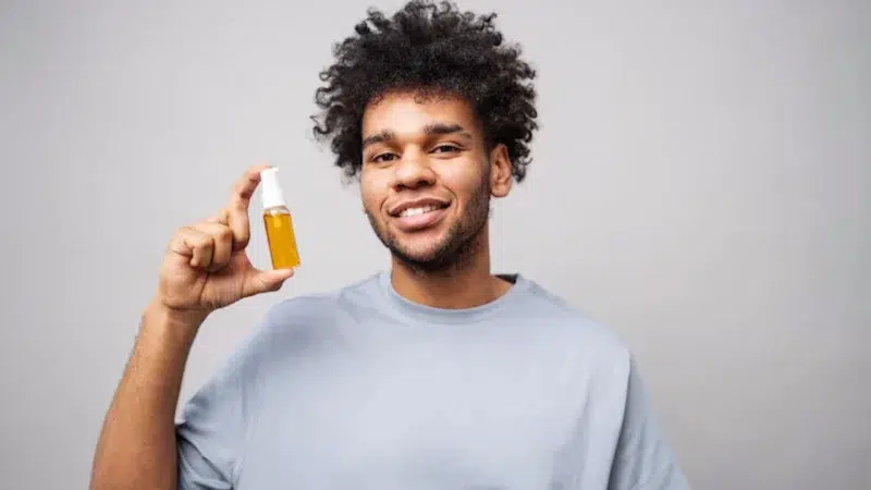 Un jeune homme qui tient un flacon avec un liquide jaune à l'intérieur
