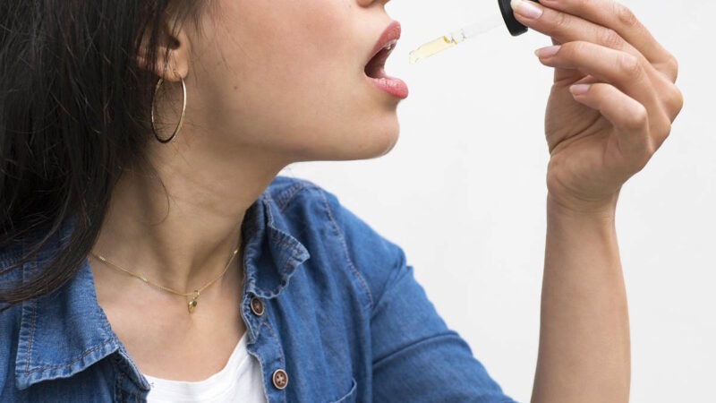 Une femme qui prend de l'huile avec une pipette