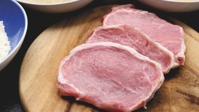 Des tranches de viandes de porc posées sur une surface en bois