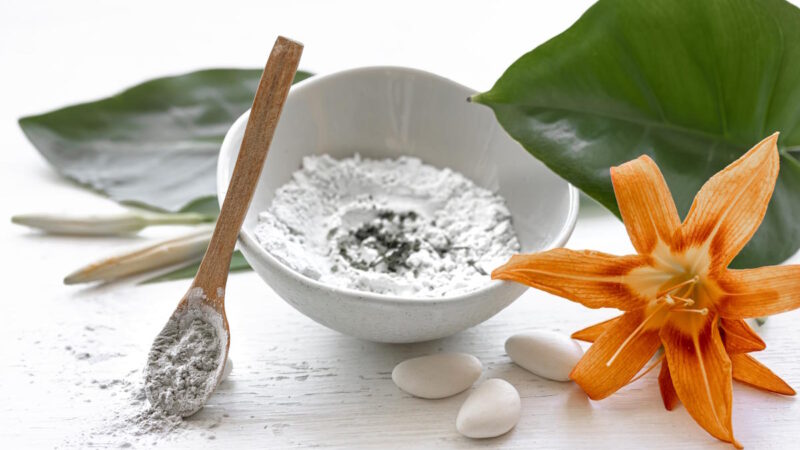 de la poudre dans un bol blanc à côté d'une fleur